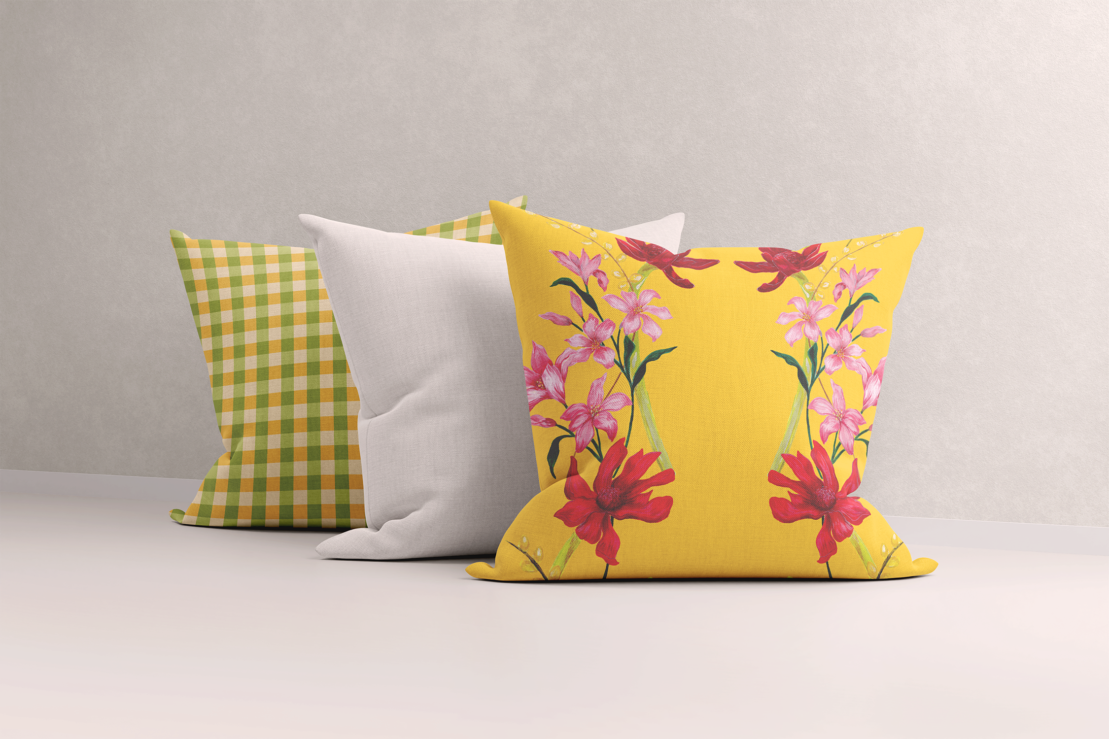 Trio of cushions against a plain backdrop featuring a yellow gold tropical floral print, plain white, and citrus gingham designs. The vibrant, hand-painted patterns offer joyful decor, showcasing the mix-and-match coordination and colourful, unique designs ideal for adding a lively touch to any space.