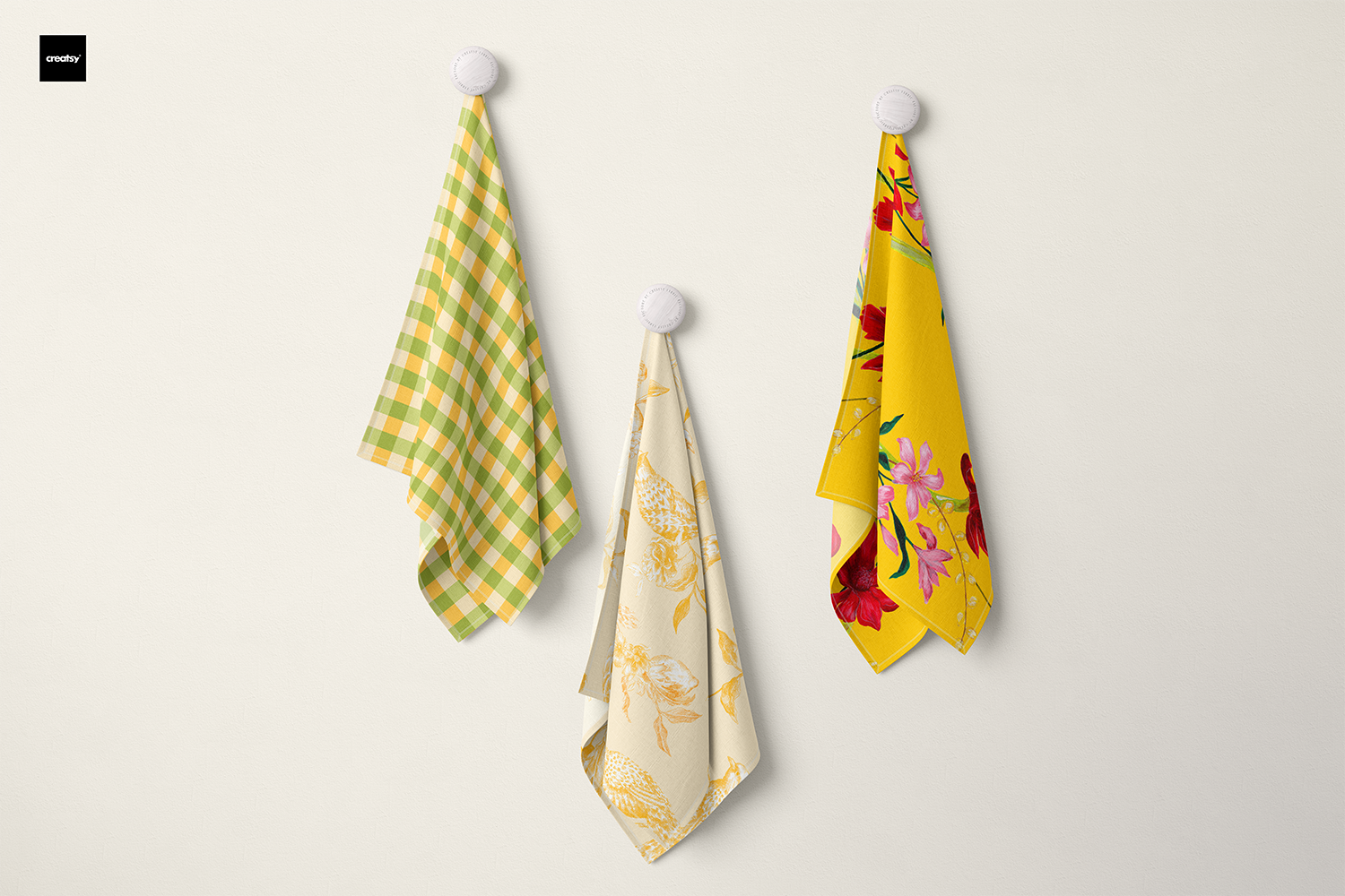 Three tea towels hanging on hooks: one with a golden tropical floral design, one with a whimsical citrus print featuring lemons and birds, and one with vibrant green gingham. Bold, bright, and colourful, adding a joyful touch to any kitchen.